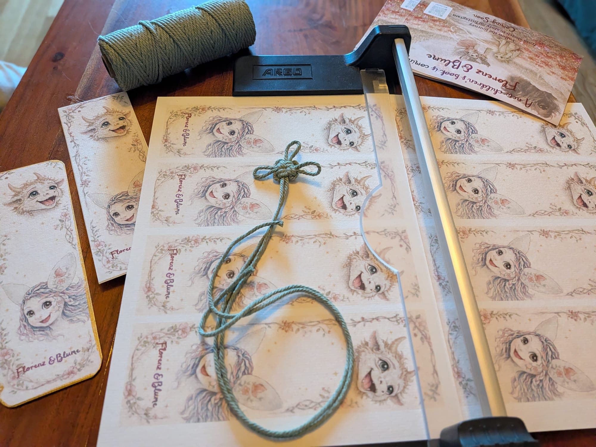 Cutting the printed bookmark sheets by hand, beside the green cord