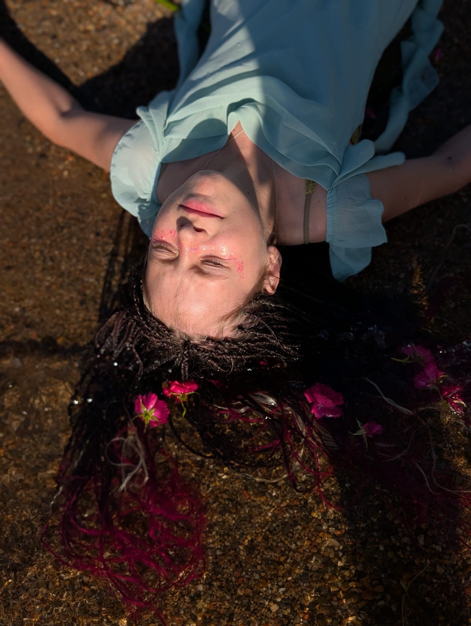 Lying back in shallow water with the braids fanned out and blossoms caught between them