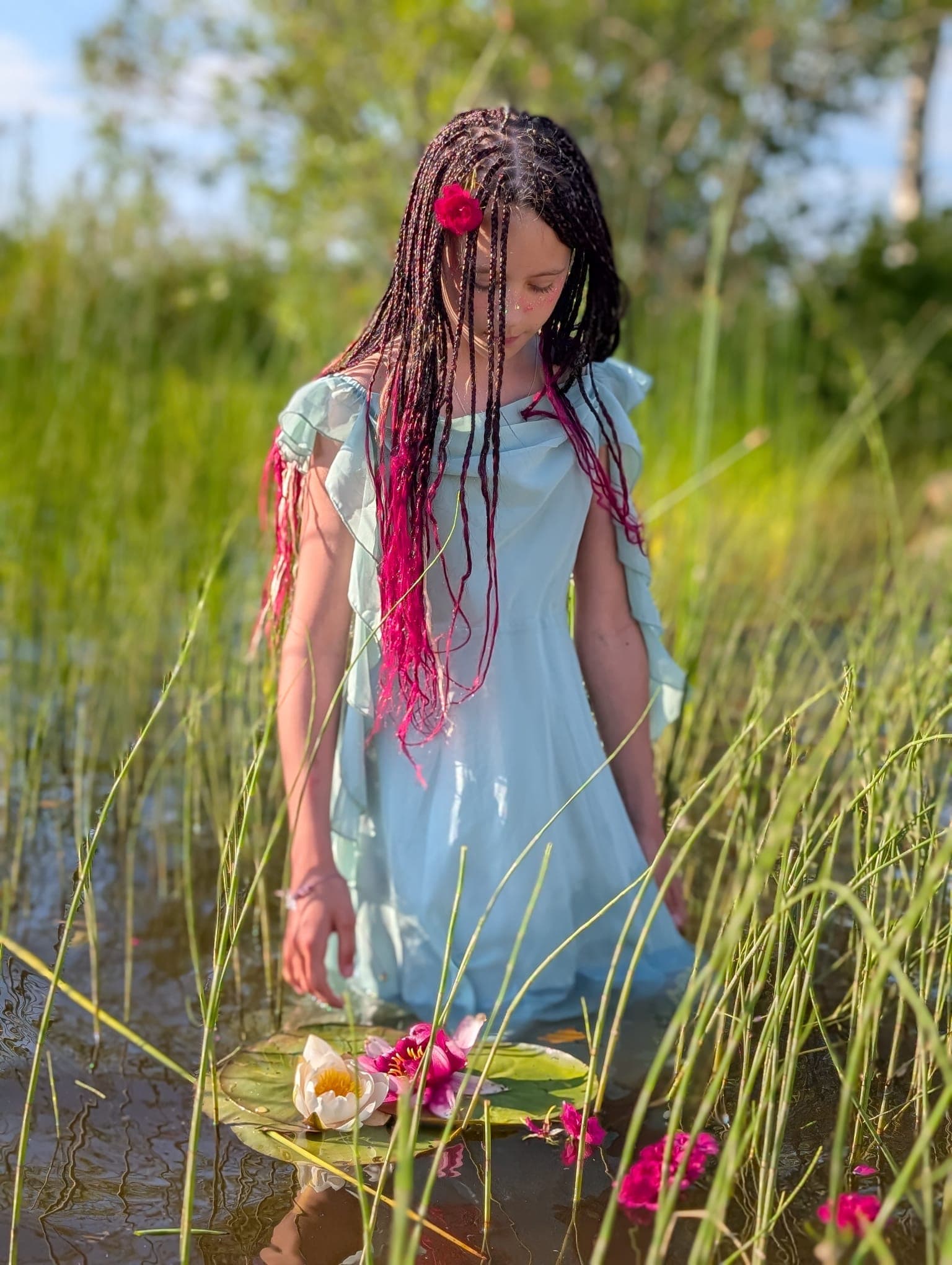 The same braids seen from further back, water lilies floating on a leaf at her feet