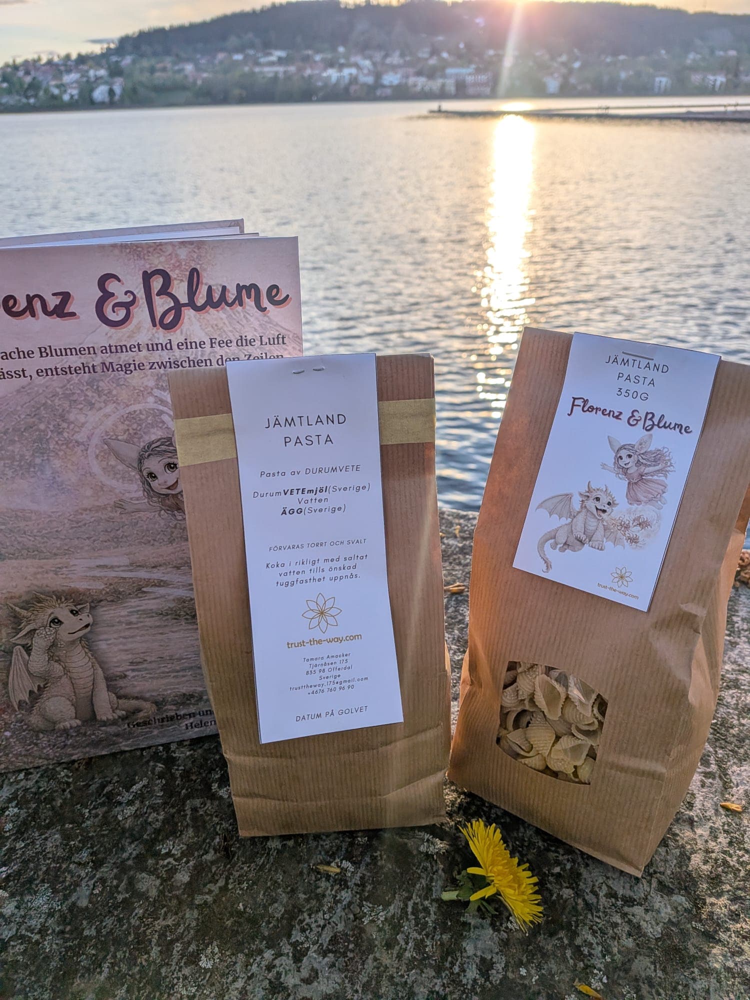 The book and a bag of pasta set out at the lakeside at sunset