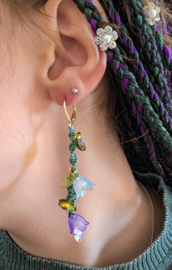 Flower drop earrings worn, the resin catching the light