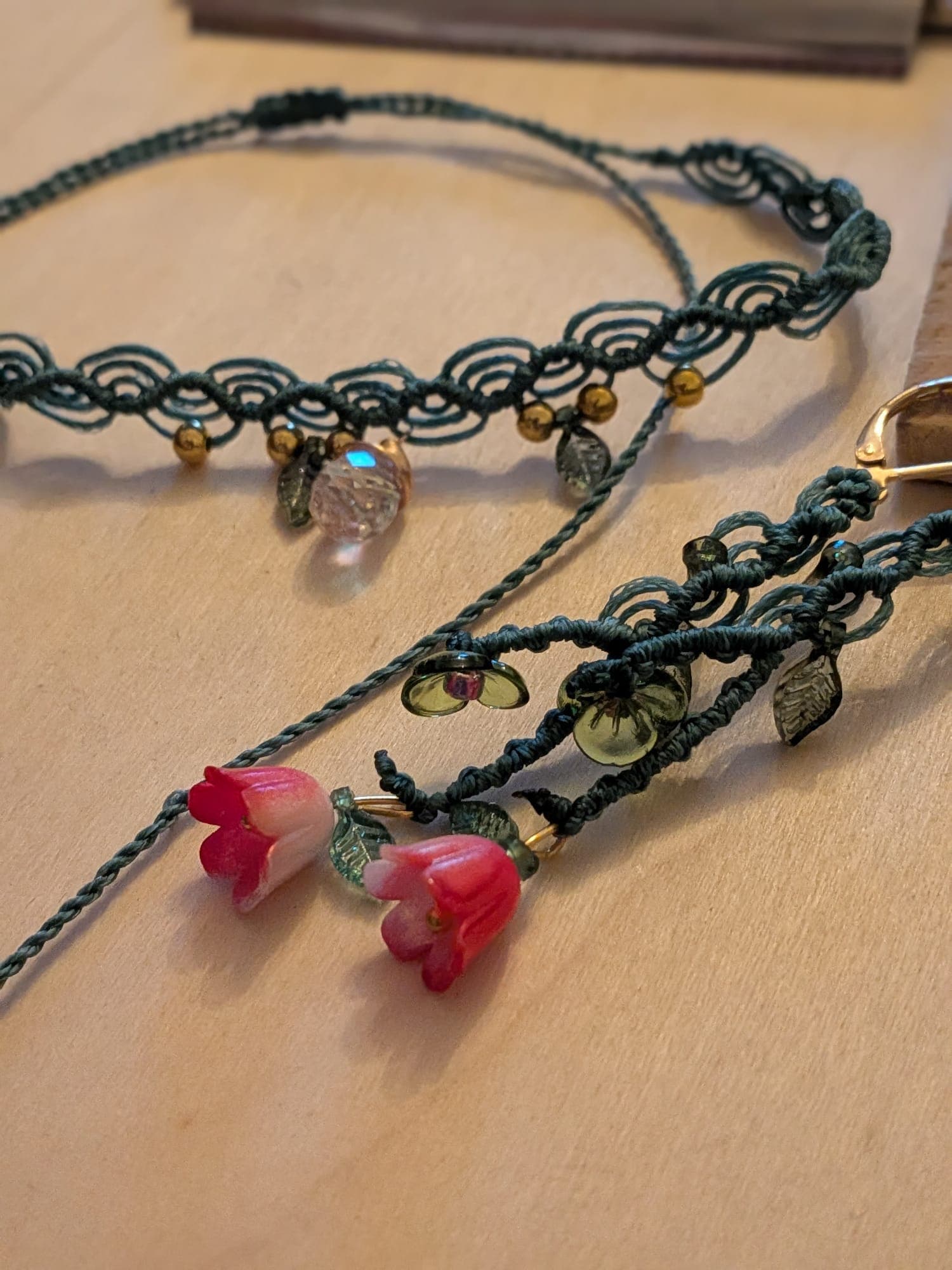 A macramé choker laid out beside the flower earrings