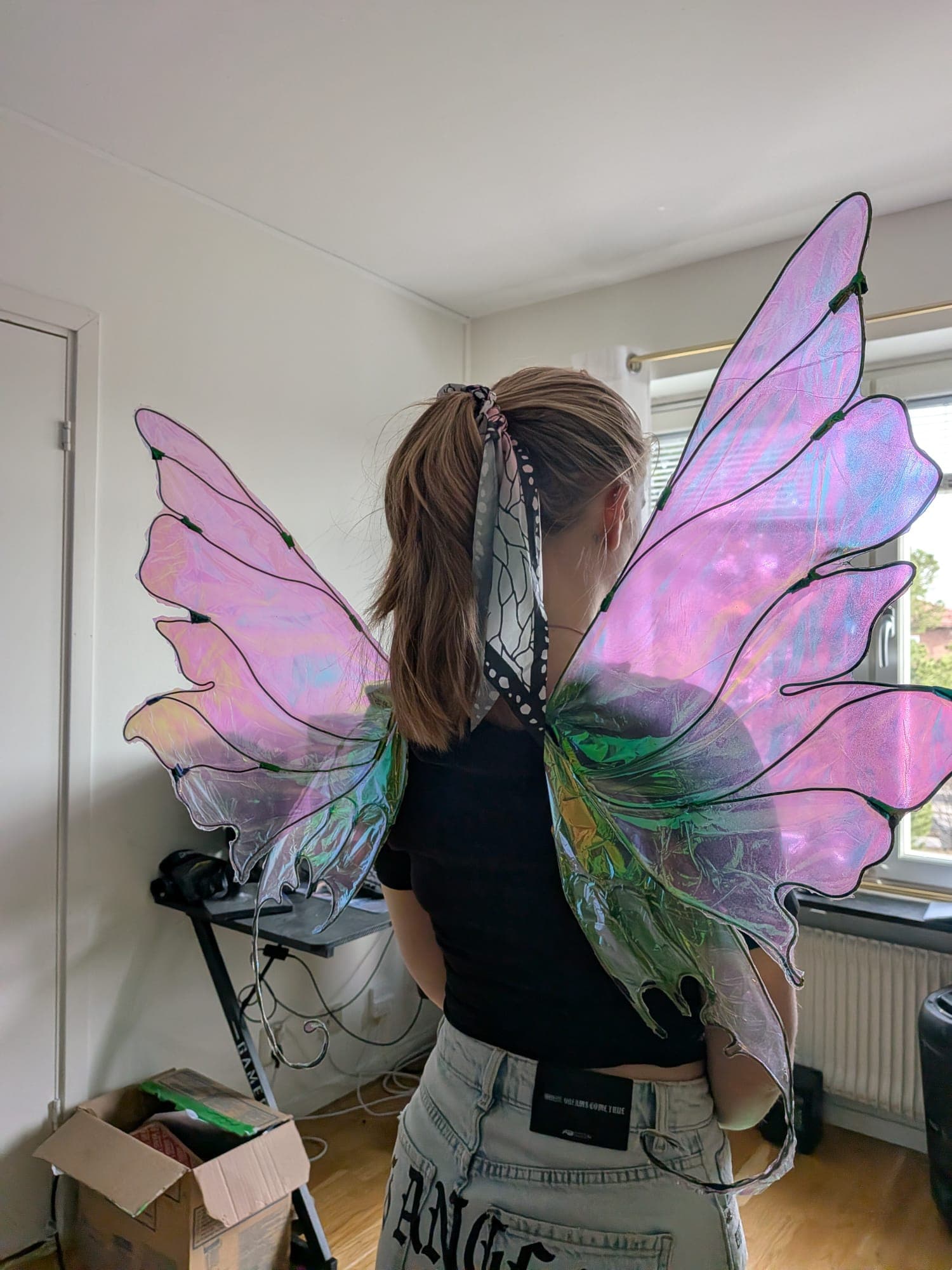 Iridescent fairy wings worn indoors, catching the light